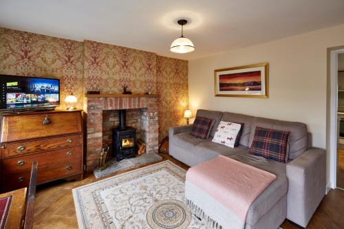 a living room with a couch and a fireplace at Maltkiln Cottage in Barbon
