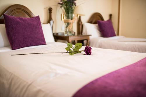 two beds with purple pillows and a flower on top at Villa de Elciego in Elciego