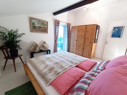 Un dormitorio con una cama con almohadas rosas y una ventana en Schwalbennest Velden, en Velden am Wörthersee