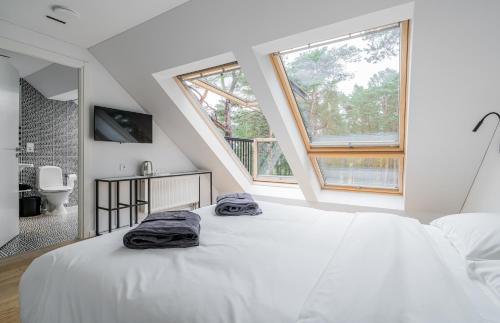 a white bedroom with a large bed and a bathroom at ESE HOTEL in Birštonas