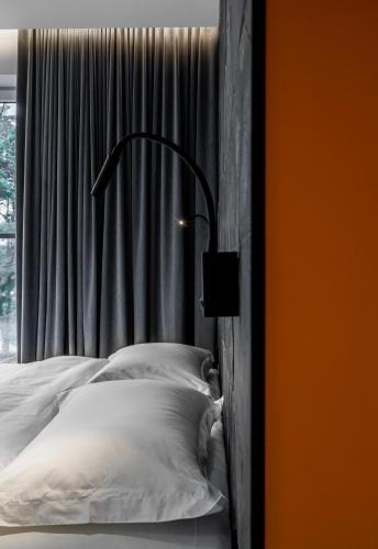 a bed with white pillows in front of a window at ESE HOTEL in Birštonas