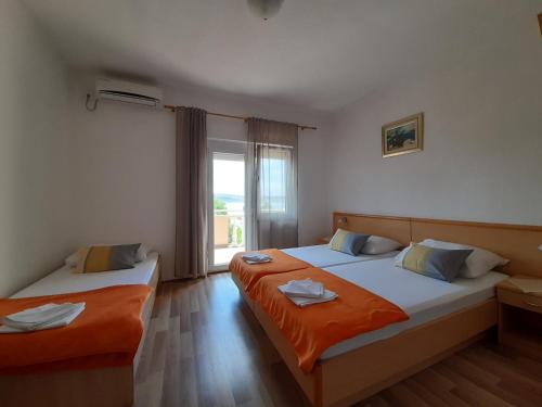 two beds in a room with a window at Apartmani Tomić in Seline