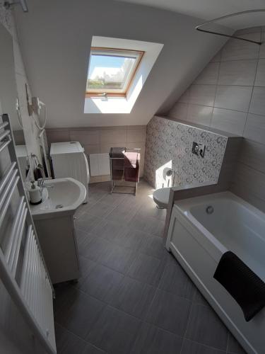 a bathroom with a sink and a bath tub and a window at Profi Kecó Apartman in Balatonalmádi