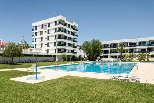 a swimming pool in front of a large building at Neptuno IV - Vilamoura in Quarteira