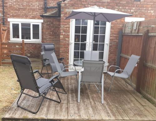 a patio with a table and chairs and an umbrella at James Cook Accommodation in Middlesbrough