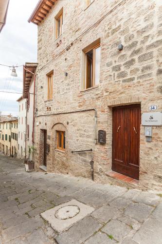 a stone building with a wooden door on a street at San Sebastiano Suite & Luxury Apartments in Colle Val D'Elsa