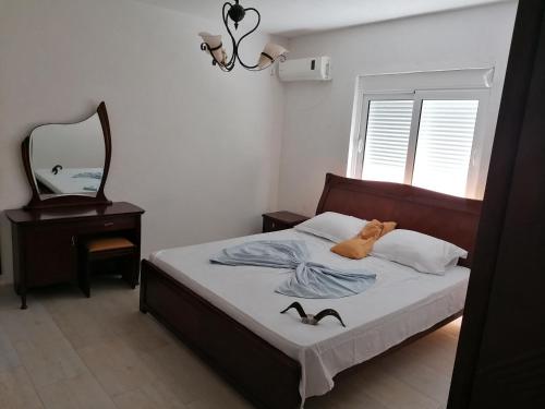 a bedroom with a bed with a teddy bear and a mirror at Vienna Montenegro Lleshi in Donji Štoj