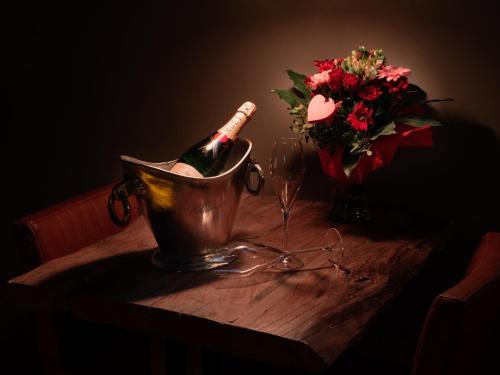 a bottle of champagne in a bucket and a vase of flowers at Dreams and Wellness in Vorstenbosch