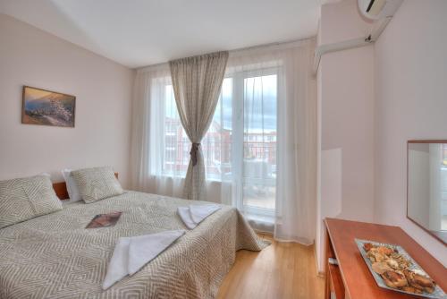 a bedroom with a bed and a large window at Privilege Beach Apartments in Sveti Vlas