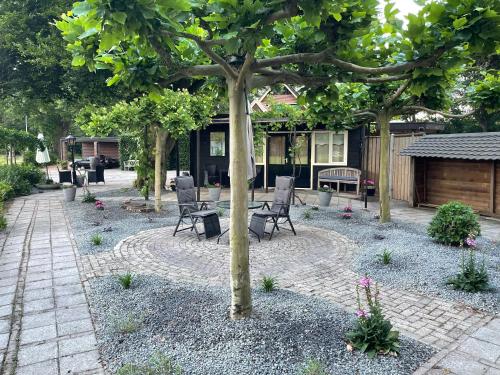 a patio with chairs and a tree in a yard at B&B Usselo Klein, fijn en uniek! in Enschede
