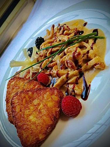 a plate of food with a piece of fish and raspberries at Meister BÄR HOTEL Fichtelgebirge in Marktredwitz