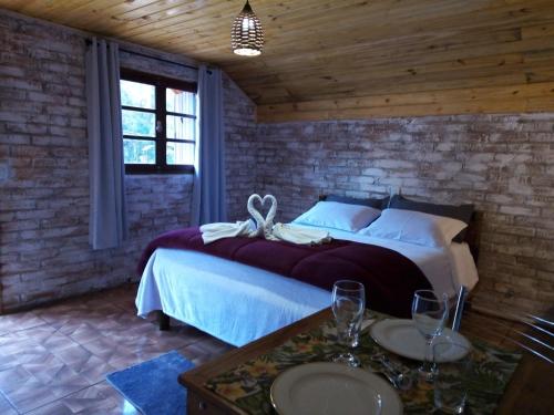 a bedroom with a large bed in a brick wall at Pousada Duplátanos in Monte Verde
