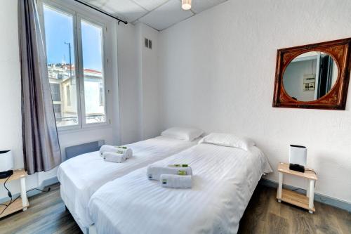 - une chambre blanche avec 2 lits et un miroir dans l'établissement IMMOGROOM - Charming apartment - City Center - Wifi - AC, à Cannes