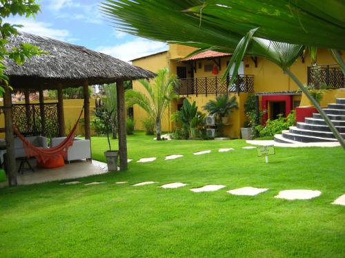 a yard with a house and a hammock in the grass at Hotel Aconchego Porto de Galinhas in Porto De Galinhas