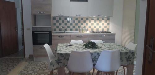 a kitchen with a table with white chairs and a kitchen with a stove at Finestra sul porto in Marina di Camerota