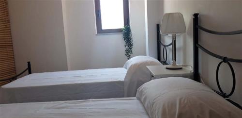 a bedroom with two beds and a table with a lamp at Finestra sul porto in Marina di Camerota