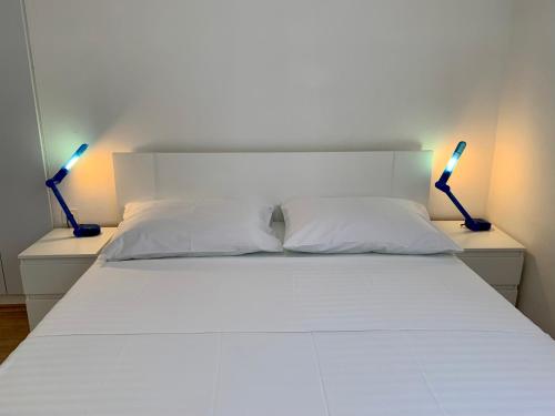 een slaapkamer met een wit bed met twee lampen bij Apartments Parać in Petrcane