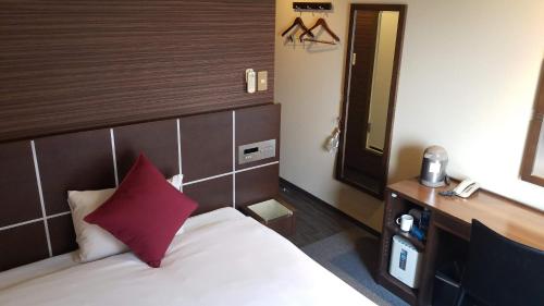 um quarto de hotel com uma cama com uma almofada vermelha em MyHotel Okazaki em Okazaki