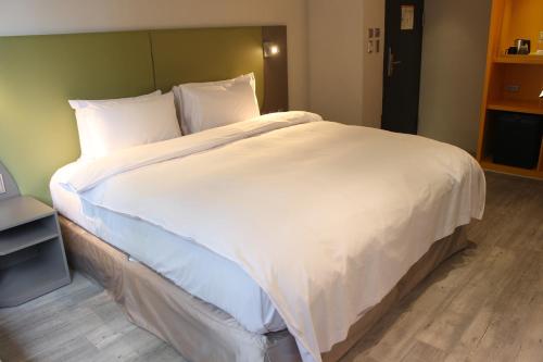 a large white bed in a hotel room at Horizon Inn in Taipei