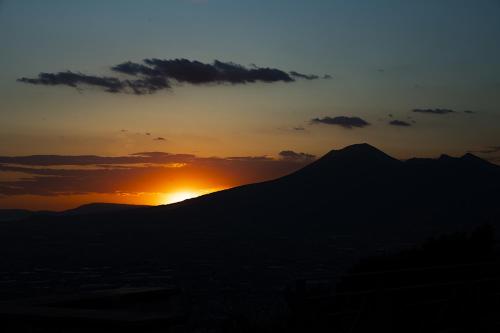 a sunset over a mountain with the sun setting at Green Park in Corbara