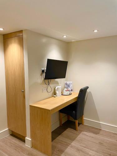 a desk with a computer monitor and a chair at Holtwhites Hotel in Enfield