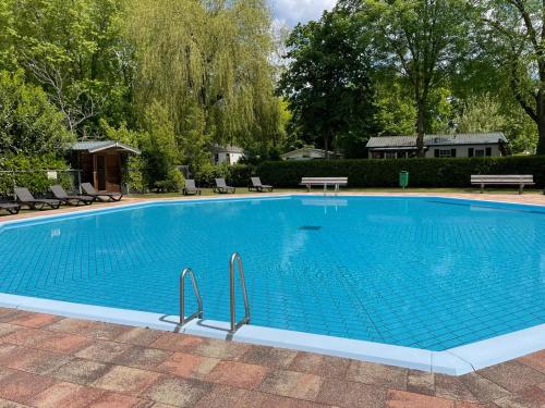 une grande piscine bleue avec des chaises et des arbres dans l'établissement Gasterij Hotel Dennenoord, à Boxtel