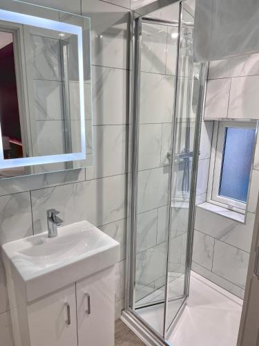 a white bathroom with a shower and a sink at Holtwhites Hotel in Enfield