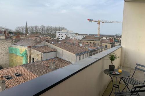 un balcon avec une table et une vue sur une ville dans l'établissement Appartement dernier étage, balcon, parking gratuit !, à Bordeaux
