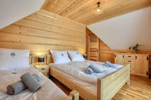 two beds in a room with wooden walls at Między Nami Góralami, domek na Podhalu, Gorce in Huba