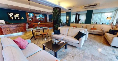 una sala de estar con sofás blancos y una mesa. en Helios Beach Hotel, en Milano Marittima
