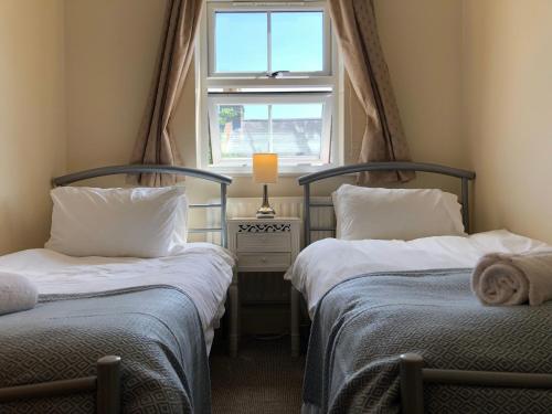 two twin beds in a room with a window at Garfield Place Cosy 2-Bedroom Cottage Central Windsor with Parking in Windsor