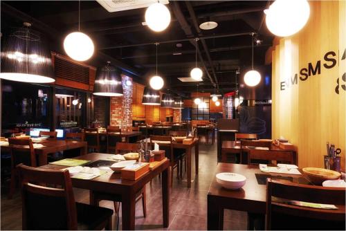 un ristorante con tavoli e sedie in legno e luci di Ulsan City Hotel a Ulsan