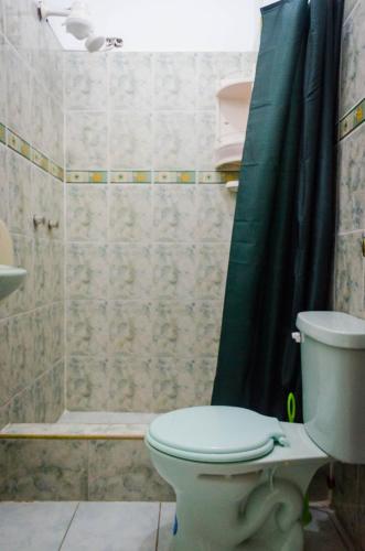 baño con aseo y cortina de ducha verde en Casa de Huespedes "Darling", en Puerto Baquerizo Moreno