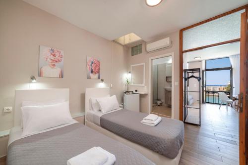 two beds in a room with a balcony at Faros Rooms in Rethymno Town