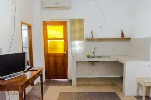 eine Küche mit einem Waschbecken und einem Schreibtisch mit einem TV in der Unterkunft Casa de Huespedes "Darling" in Puerto Baquerizo Moreno