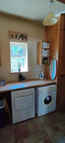 a kitchen with a washing machine and a window at Ferry View Cottage in Belmullet