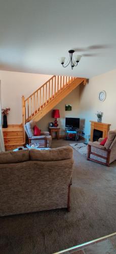 a living room with two couches and a staircase at Ferry View Cottage in Belmullet