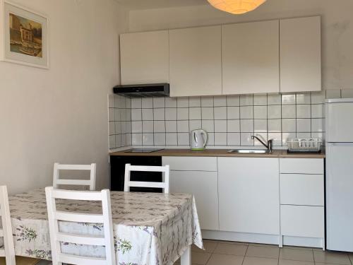uma cozinha com armários brancos e uma mesa e cadeiras em Apartments Parać em Petrcane