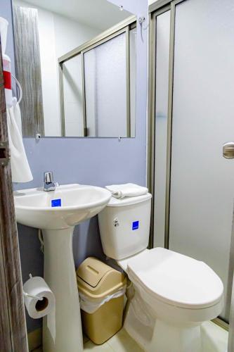 a white bathroom with a toilet and a sink at Luna Cartagena Airport Hotel in Cartagena de Indias
