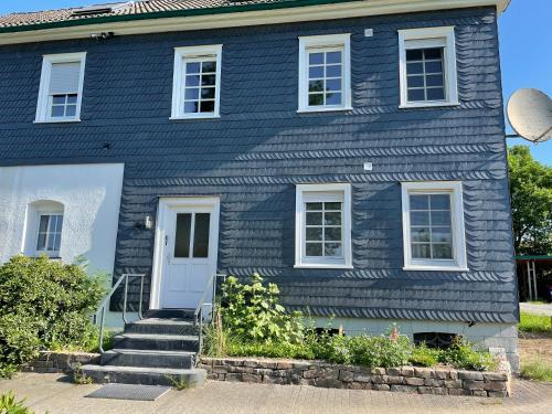 a blue house with a white door and stairs at Ferienwohnung Annika in Hückeswagen