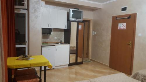a small kitchen with a table and a tv on the wall at Apartments Dani in Pomorie