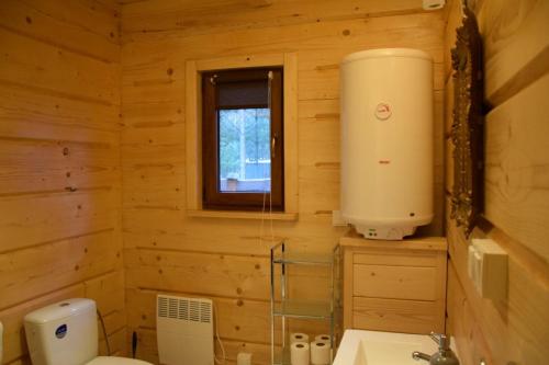 a log cabin bathroom with a toilet and a window at Zacisze Leśne- Domek do wynajęcia in Tereszpol Zaorenda