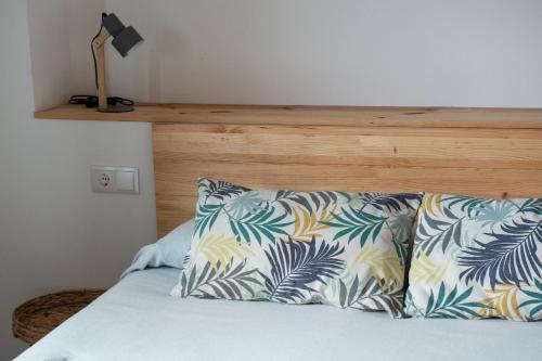 a bed with a wooden headboard and pillows on it at La Casita de Melón in Suances