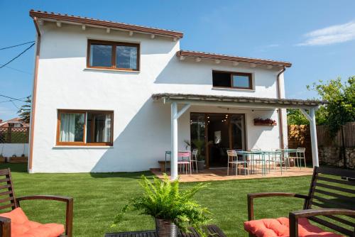 a white house with a patio in the yard at La Casita de Melón in Suances