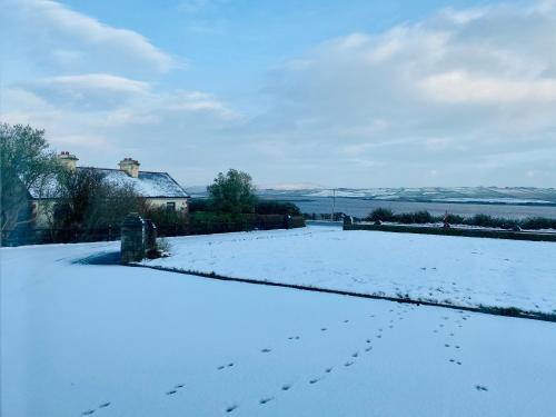 a snow covered yard with footprints in the snow at Ferry View Cottage in Belmullet