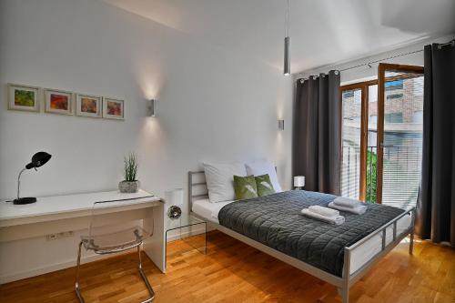 a bedroom with a bed with a desk and a window at Apartamenty Prestige Browar Lubicz Stare Miasto in Krakow