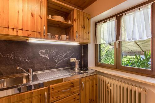 eine Küche mit einer Tafel, einem Waschbecken und einem Fenster in der Unterkunft Ferienwohnung Heinrich in Gmund am Tegernsee