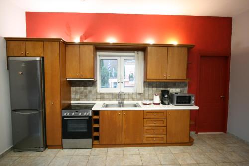 a kitchen with wooden cabinets and a red wall at Quality Suite, Tranquility, Sea Views, Breeze in Agios Gordios