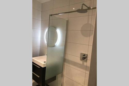 a bathroom with a shower with a sink and a mirror at Sas van Gent, luxe appartement in centrum in Sas van Gent