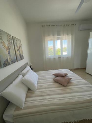 een witte slaapkamer met een groot bed met 2 kussens bij SINE TEMPORE Beach Holiday Home in Maruggio